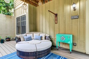 A cozy outdoor seating area with a round cushioned bench, a small table, and a wall-mounted light fixture. - Bear Bluff - Game Room, Fire Table, Comfy Patio + Community Activities (Jasper)
