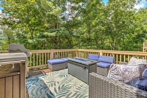 A deck with a grill, a table with blue cushions, and a patterned rug. - Bear Bluff - Game Room, Fire Table, Comfy Patio + Community Activities (Jasper)