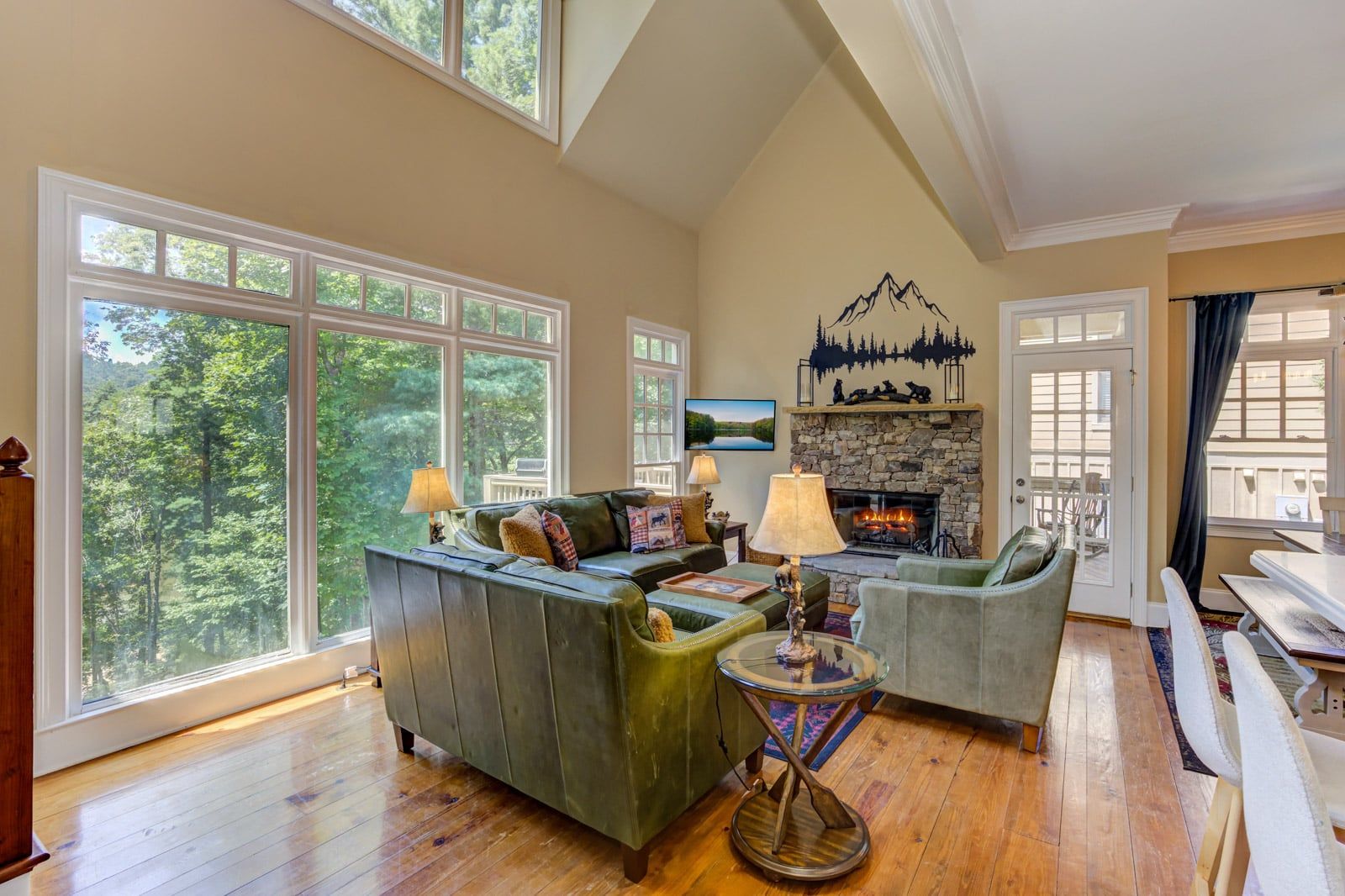 A spacious living room with a fireplace, large windows, and a view of the outdoors.