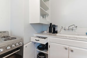 A kitchen with a stove, a sink, and a cabinet with a drawer.