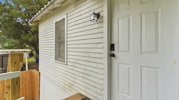 A white wooden house with a front door, a window, and a small porch.