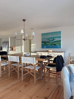 Een moderne keuken met witte kasten, een houten eettafel en een kroonluchter.