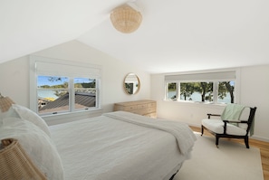 A bedroom with a large bed, a dresser, a chair, and two windows offering a view of a lake. - East Hampton 4 BR waterfront - Water views - every room! (East Hampton)