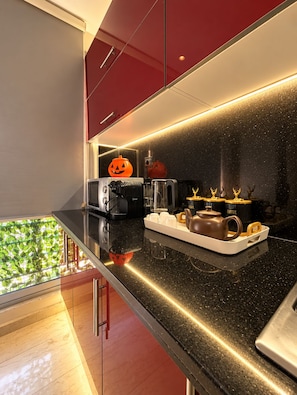 A modern kitchen with a black countertop, red cabinets, and a coffee station. - Ideal, 2 bedrooms, 2 bathrooms, fiber optic internet, IPTV, parking, fitness (Dar-el-Beida)