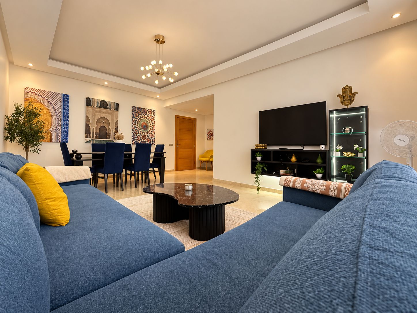Een moderne woonkamer met een bank, een eethoek en een televisie.