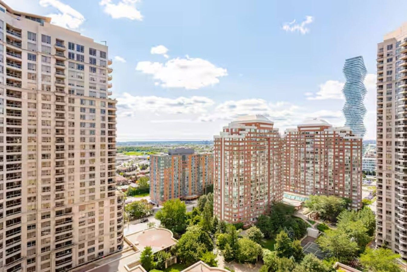 A high-rise residential building complex with multiple apartment buildings, surrounded by greenery and a clear sky.