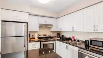 A modern kitchen with white cabinets, stainless steel appliances, and a granite countertop.