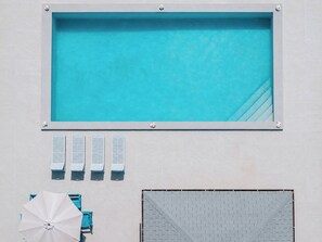 Een zwembad met betegeld zonnedek, een overdekt zitgedeelte en een overdekte patio.