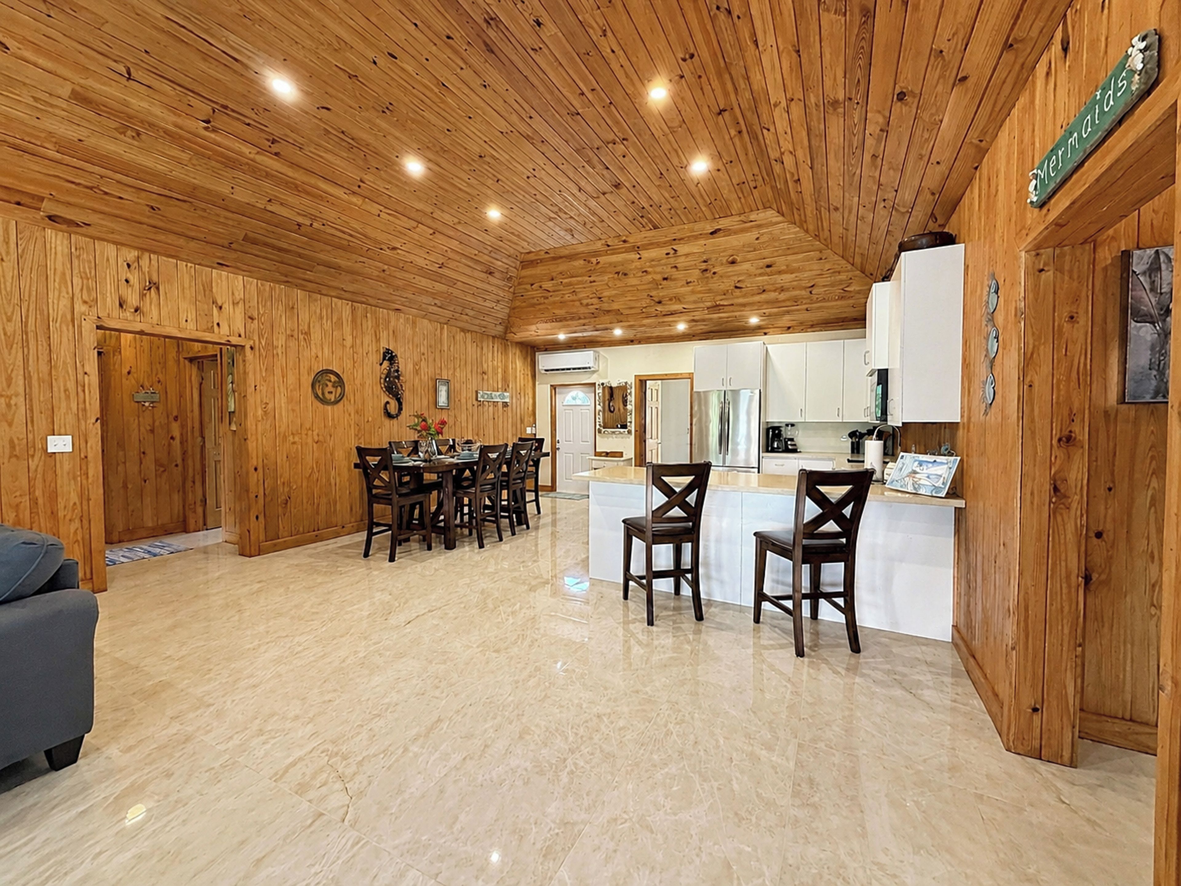 Un interior de madera con comedor, cocina y un letrero que dice 'Mermaids'.