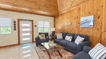 Ein geräumiges Wohnzimmer mit Holzboden, einer Sofagarnitur, einem Couchtisch und einem gemusterten Teppich.