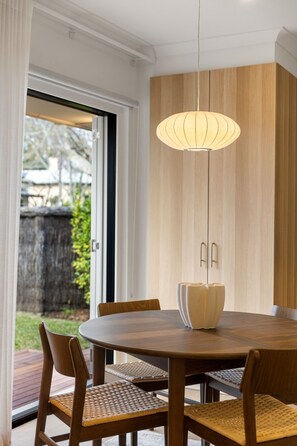 A dining area with a round table, chairs, and a hanging light fixture. - Luna—Canopy Views from a Peaceful Garden Haven (College Park)