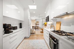 A modern kitchen with white cabinetry, a built-in oven, and a gas stove. - Luna—Canopy Views from a Peaceful Garden Haven (College Park)