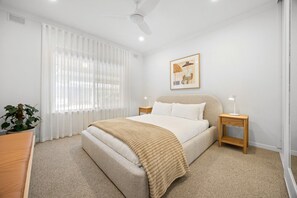 A bedroom with a bed, bedside tables, a ceiling fan, a window with curtains, and a framed picture on the wall. - Luna—Canopy Views from a Peaceful Garden Haven (College Park)