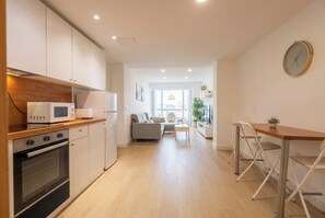 Eine moderne Küche mit Mikrowelle, Backofen und Schränken. Ein Essbereich mit Tisch und Stühlen ist ebenfalls vorhanden.