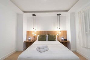 Ein modernes Hotelzimmer mit einem großen Bett, einem Holz-Kopfteil, Nachttischen mit Lampen und einem Vorhang am Fenster.