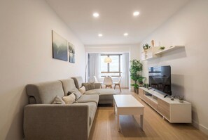 Ein modernes Wohnzimmer mit einer Couch, einem Couchtisch, einem Fernseher und einem Essbereich mit Stühlen.