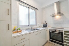 A modern kitchen with white cabinetry, a stainless steel range hood, a microwave, and a built-in oven. - Elegant Stay La Naval 2 (Las Palmas de Gran Canaria)