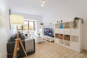 Un salon moderne comprenant un canapé, une table basse, un téléviseur et une bibliothèque.