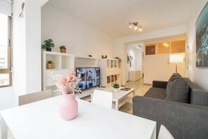 A modern living room with a flat-screen TV, a grey sofa, a white coffee table, and a pink vase with dried flowers. - Elegant Stay La Naval 3 (Las Palmas de Gran Canaria)