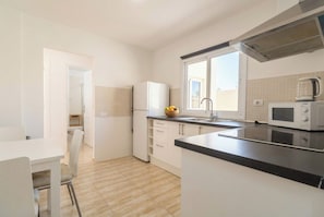 A modern kitchen with a refrigerator, microwave, and a fruit bowl on the counter. - Elegant Stay La Naval 3 (Las Palmas de Gran Canaria)