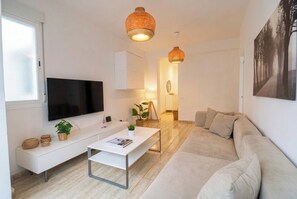A modern living room with a flat-screen TV, a white sofa, a coffee table, and two hanging lamps. - Elegant Stay La Naval 4 (Las Palmas de Gran Canaria)