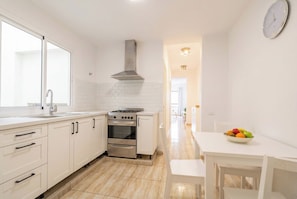 A modern kitchen with white cabinetry, a stainless steel stove, and a large window. - Elegant Stay La Naval 4 (Las Palmas de Gran Canaria)