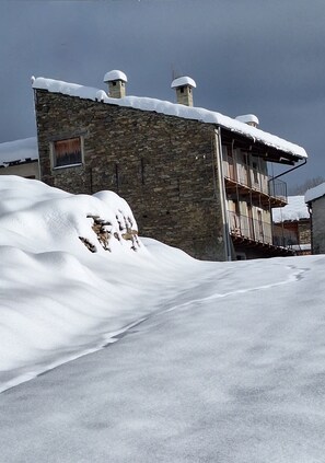 Ein Gebäude aus Stein mit einem schneebedeckten Dach und einem Balkon.