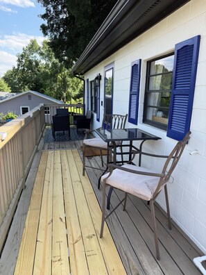 A covered outdoor patio with a wooden deck, a glass table, and two chairs. - Cozy Apartment Flip-Flop up to the Lake Marina + Outdoor Fun (Mooresville)