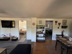 A modern living room with a flat-screen TV, a coffee bar, and a dining area with a bench. - Cozy Apartment Flip-Flop up to the Lake Marina + Outdoor Fun (Mooresville)