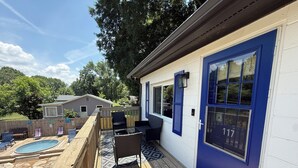 Une terrasse avec des meubles d’extérieur, une piscine et une maison avec une porte bleue.