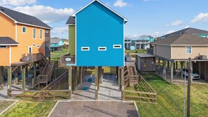 Ein Wohngebiet mit Häusern, die Holzbalkone besitzen, und einem zentral gelegenen, blauen Gebäude mit Satteldach.