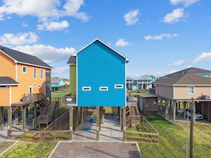 Un quartiere residenziale con case dotate di terrazze in legno e un edificio centrale blu con tetto a punta.