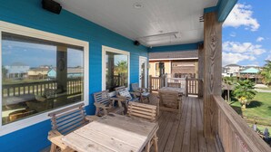 Eine Holzterrasse mit Gartenmöbeln, großen Fenstern und Blick auf benachbarte Häuser.