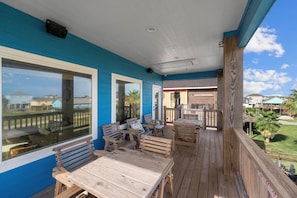 Un terrazzo in legno con mobili da esterno, ampie finestre e vista sulle case vicine.