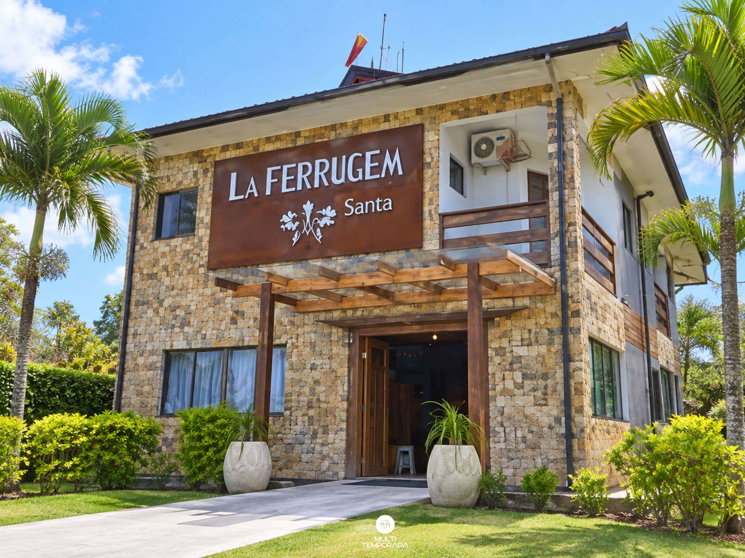 Un edificio de dos pisos con fachada de piedra, un letrero que dice 'LA FERRUGEM Santa' y una entrada cubierta.