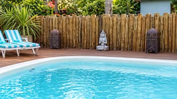 Una piscina con sillones de descanso y una estatua de Buda.