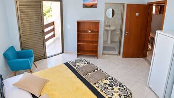 Une chambre à coucher comprenant un lit, une armoire, un bureau, une chaise, une salle de bain et un réfrigérateur.
