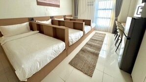 Une chambre d’hôtel avec un grand lit, un bureau, un réfrigérateur et une fenêtre avec des rideaux.