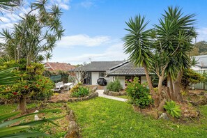 A residential property with a garden, a patio, and a house with a tiled roof. - Aura by Coast Hosting (Terrigal)
