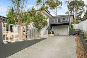 A residential property with a concrete driveway, a fenced garden, and a garage. - Aura by Coast Hosting (Terrigal)