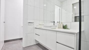 A modern bathroom with white cabinetry, a large mirror, and a white sink.