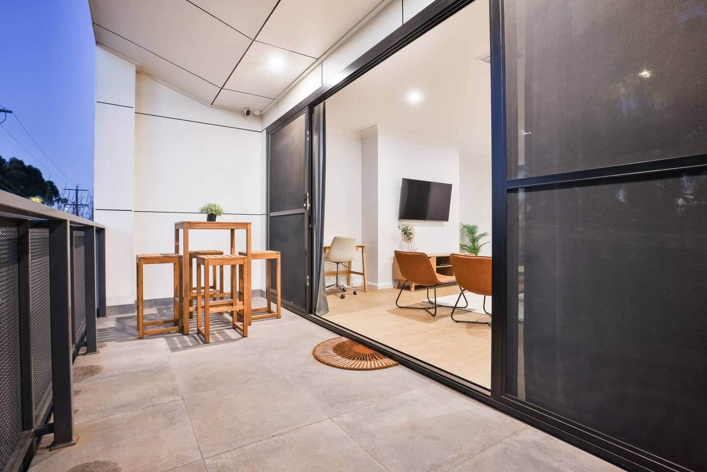 A modern interior with a sliding glass door leading to a living area with a sofa, chairs, and a TV.