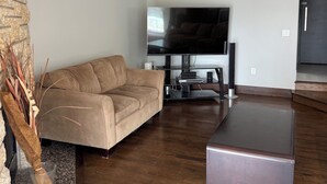 Ein modernes Wohnzimmer mit einer Eckcouch, einem Flachbildfernseher und einem Couchtisch.