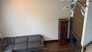 Ein modernes Wohnzimmer mit einer Eckcouch, einem Holztisch, einer dekorativen Leuchte und einer Holztreppe.