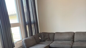 Ein modernes Wohnzimmer mit einem Ecksofa, einem kleinen Hocker und einem Couchtisch aus Holz.