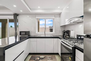 Eine moderne Küche mit schwarzer Arbeitsplatte, weißen Schränken, einem eingebauten Backofen und einem Fenster mit Blick.