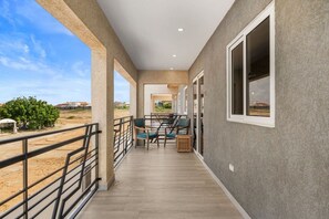 A covered outdoor area with a wooden floor, metal railing, and a seating area with chairs and tables. - 2BR Aruba Getaway w/ Pool & BBQ, Near Eagle Beach (Oranjestad)