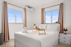 A hotel room with a bed, bedside tables, a nightstand, a window, and an air conditioning unit. - 2BR Aruba Getaway w/ Pool & BBQ, Near Eagle Beach (Oranjestad)