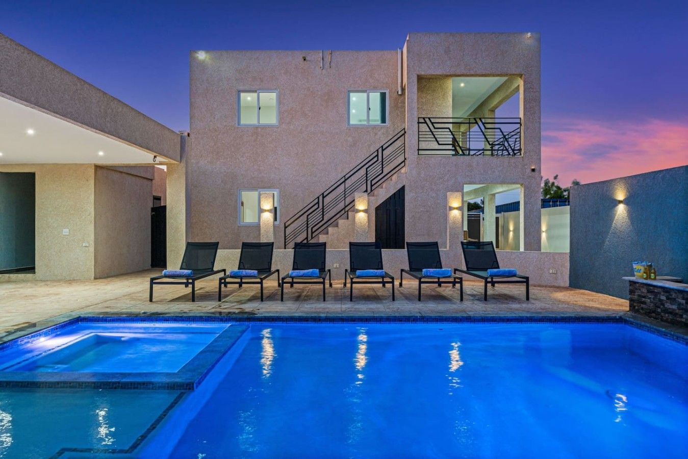 A modern two-story building with a swimming pool and outdoor seating area.