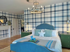 A bedroom with a bed, nightstands, a dresser, a mirror, and a chandelier.